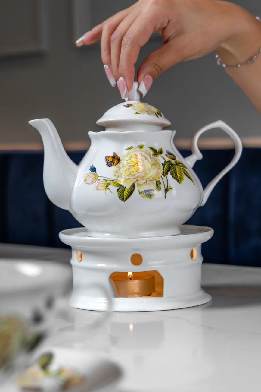 Floral teapot warmed by a small candle