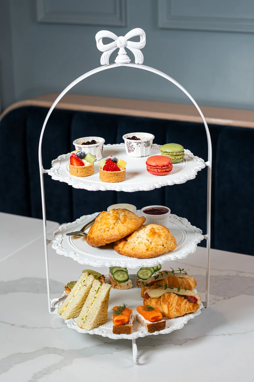 Three-tier afternoon tea stand with pastries, scones and savory bites